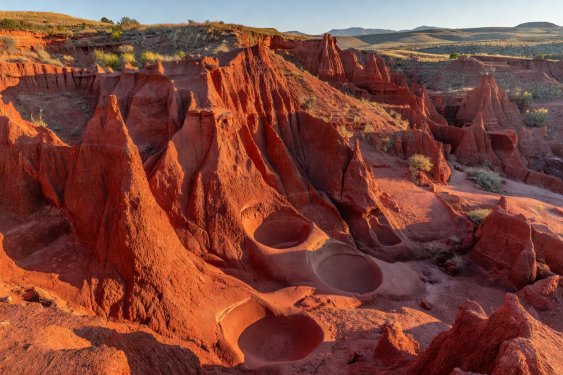 Pinnacles of orange-red sediment surrounded by green woodland at Las Médulas